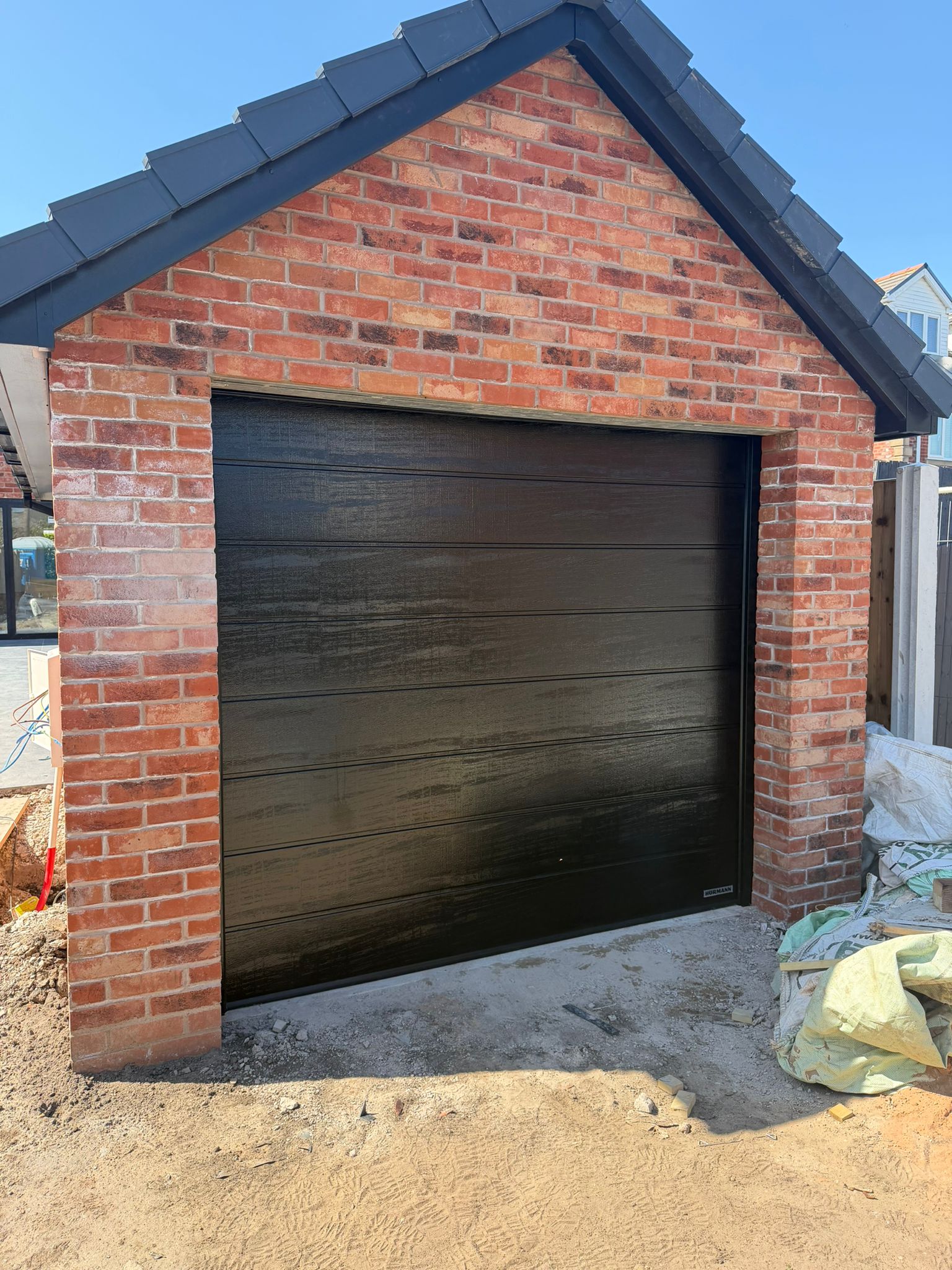 Detached brick garage with apex roof and modern black door
